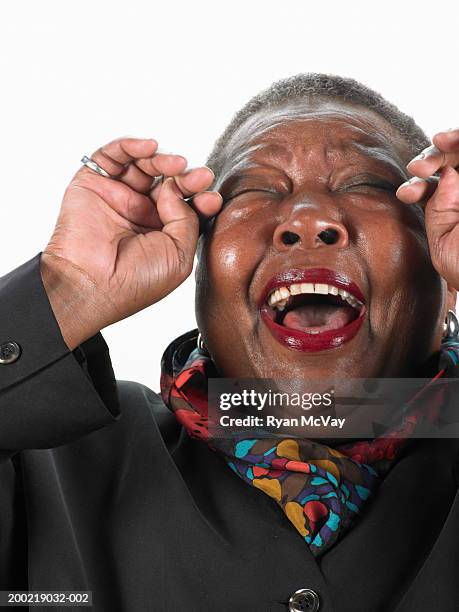 mature woman laughing, wiping tears from eyes - rie y llora fotografías e imágenes de stock
