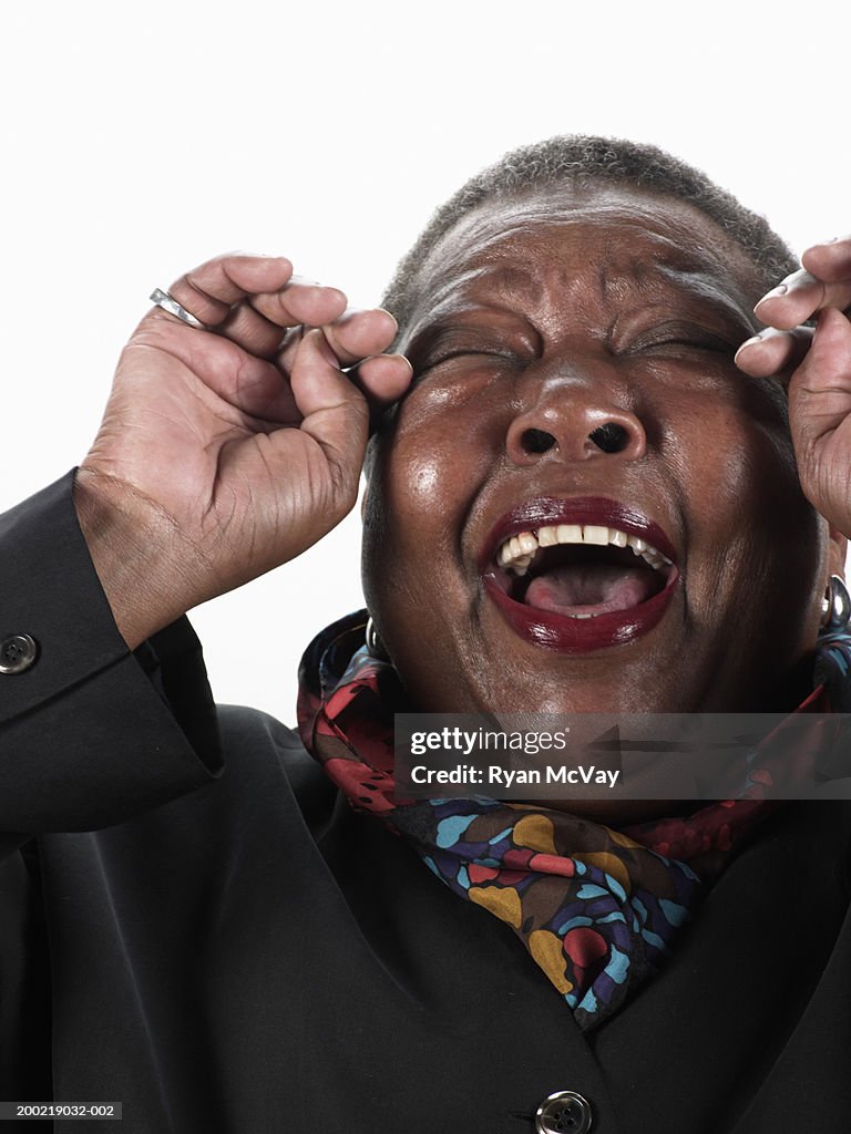 Mature woman laughing, wiping tears from eyes