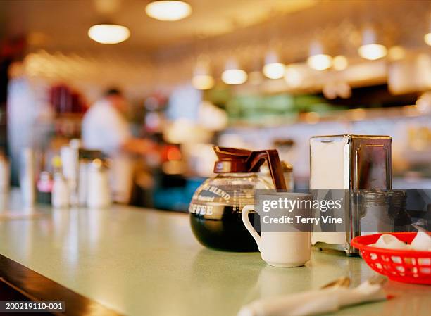 diner counter top with coffee pot and cup next to napkin dispenser - imbiss stock-fotos und bilder