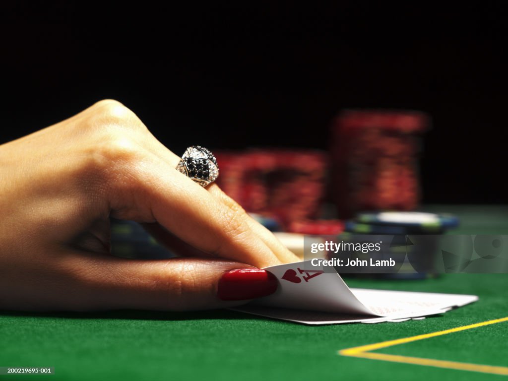 Woman lifting card on casino table, close-up