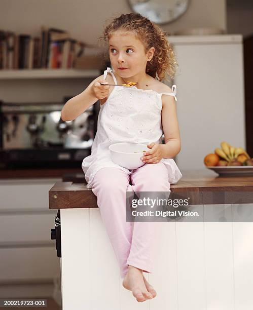 girl (4-6) sala de estar con cocina contador comía cereal, mirando a - cereals fotografías e imágenes de stock