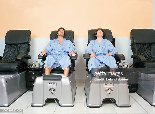 two young men at spa soaking feet before pedicure - man pedicure chair stock pictures, royalty-free photos & images