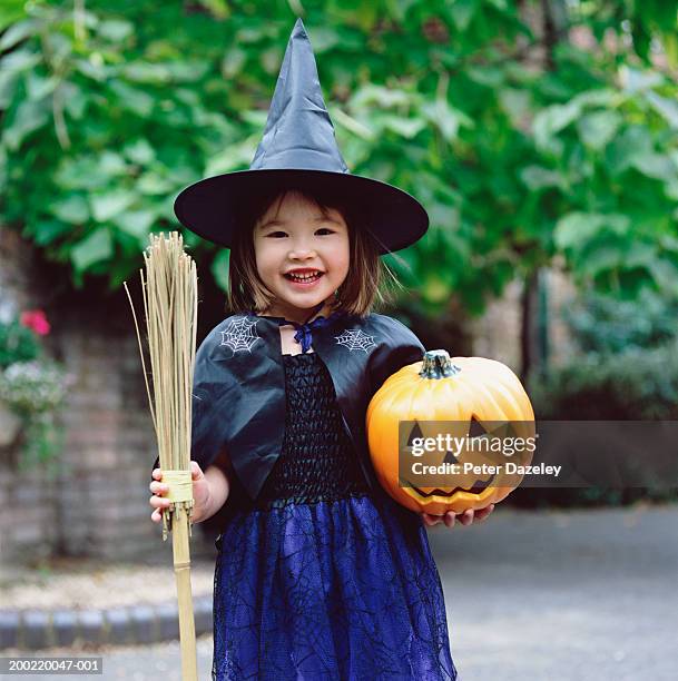 girl (3-5) dressed as witch, holding pumpkin and broom, portrait - halloween kids stockfoto's en -beelden