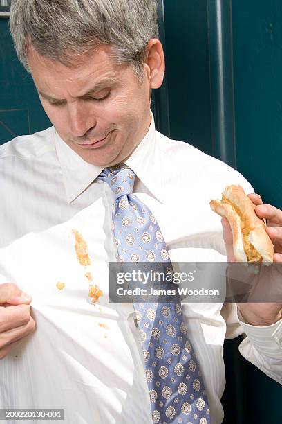 businessman outdoors, hotdog sauces spilt on shirt, close-up - 40's rumpled business man stockfoto's en -beelden
