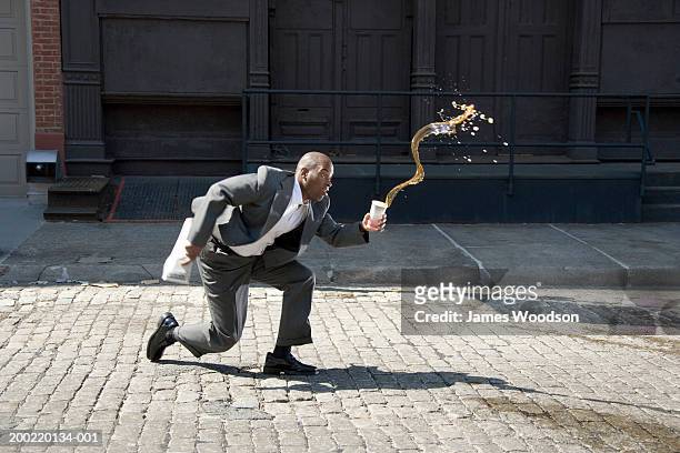 businessman outdoors, spilling cup of coffee on pavement, side view - cadere foto e immagini stock