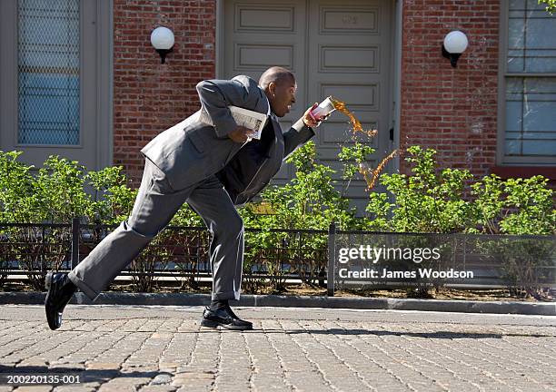 businessman outdoors, spilling cup of coffee on pavement, side view - coffee drop stock pictures, royalty-free photos & images