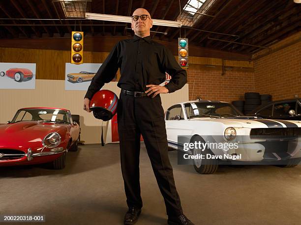 mature man holding helmet in garage, portrait, low angle view - car racing helmet stock pictures, royalty-free photos & images