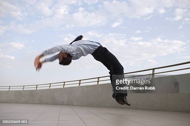 businessman backflipping on balcony, side view (blurred motion) - backflipping fotografías e imágenes de stock