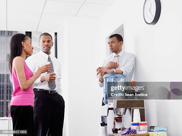 businesspeople talking by water cooler - dispensador de agua fotografías e imágenes de stock