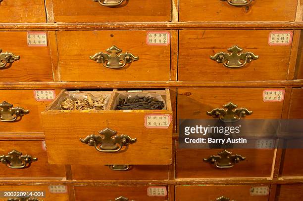 cabinet in chinese herb store, drawer open revealing herbs - médecine chinoise par les plantes photos et images de collection