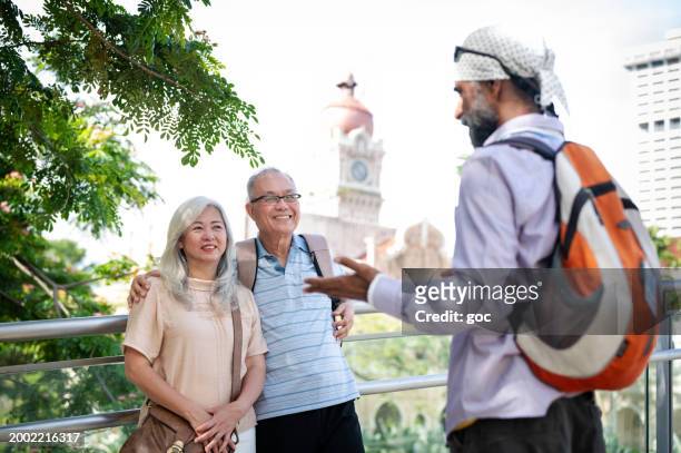a mature sikh tour guide explaining about the heritage architecture and history of the sultan abdul samad buildings to two senior asian tourist - abdul stock pictures, royalty-free photos & images