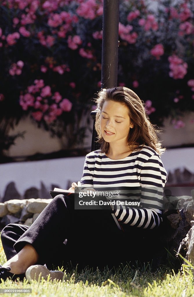 Young woman sitting in garden, drawing