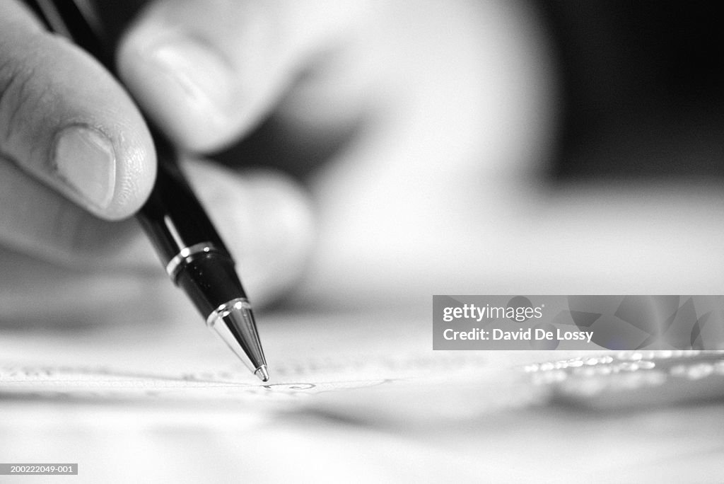 Person holding pen, close-up of hand and object, (B&W)