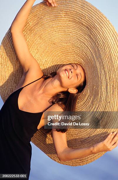 young woman wearing large straw hat - straw hat stock pictures, royalty-free photos & images