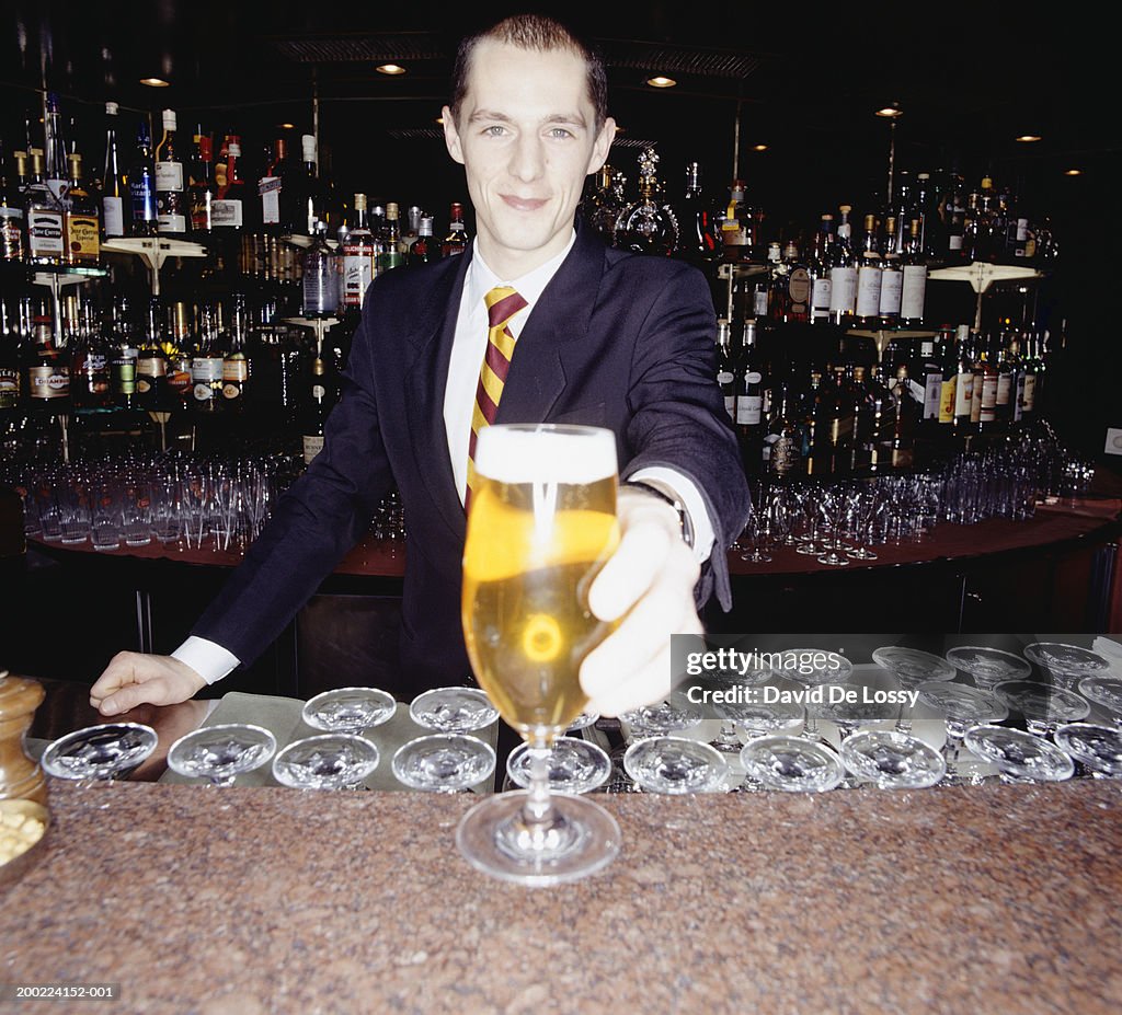 Young barman serving beer, portrait