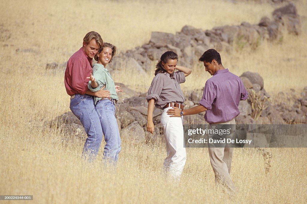 Two young couples dancing on hillside