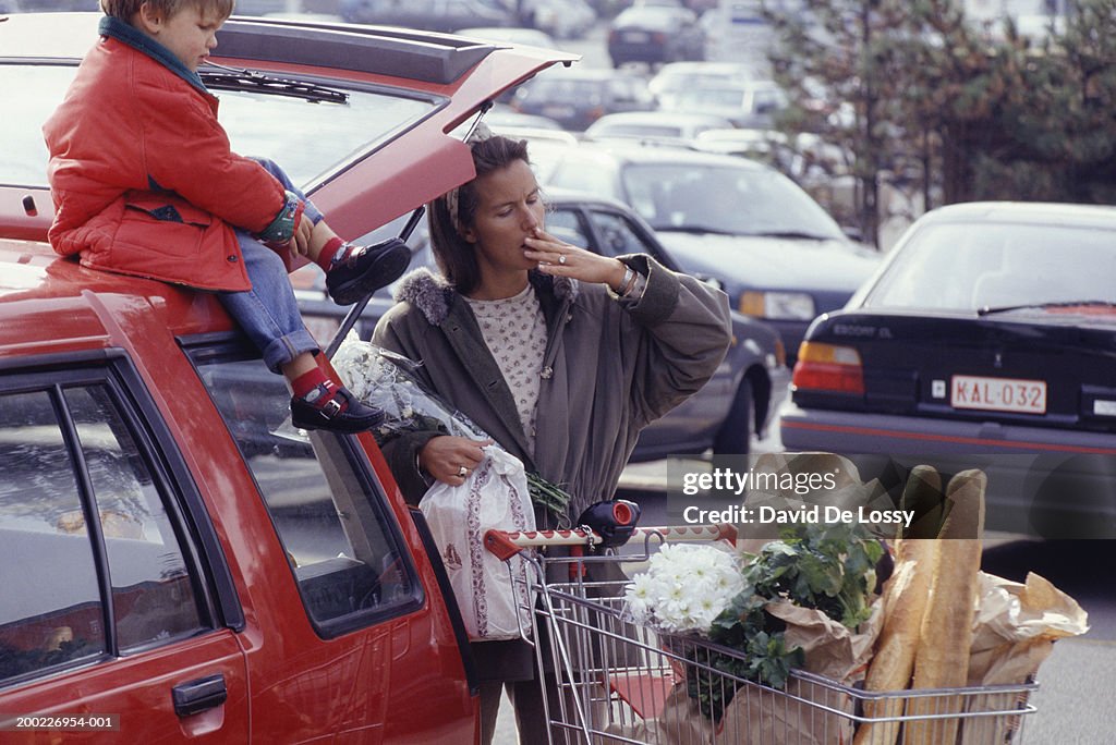Mother and child (3-4 years) in supermarket car park with shopping, three quarter length