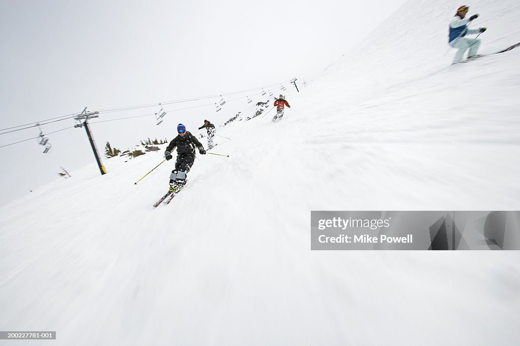 Skiers downhill skiing on slope at ski area (blurred motion)