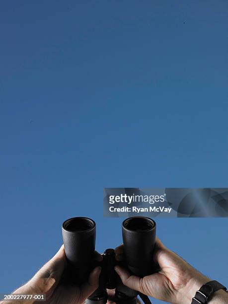 man looking through binoculars, high section, low angle view - fernglas stock-fotos und bilder