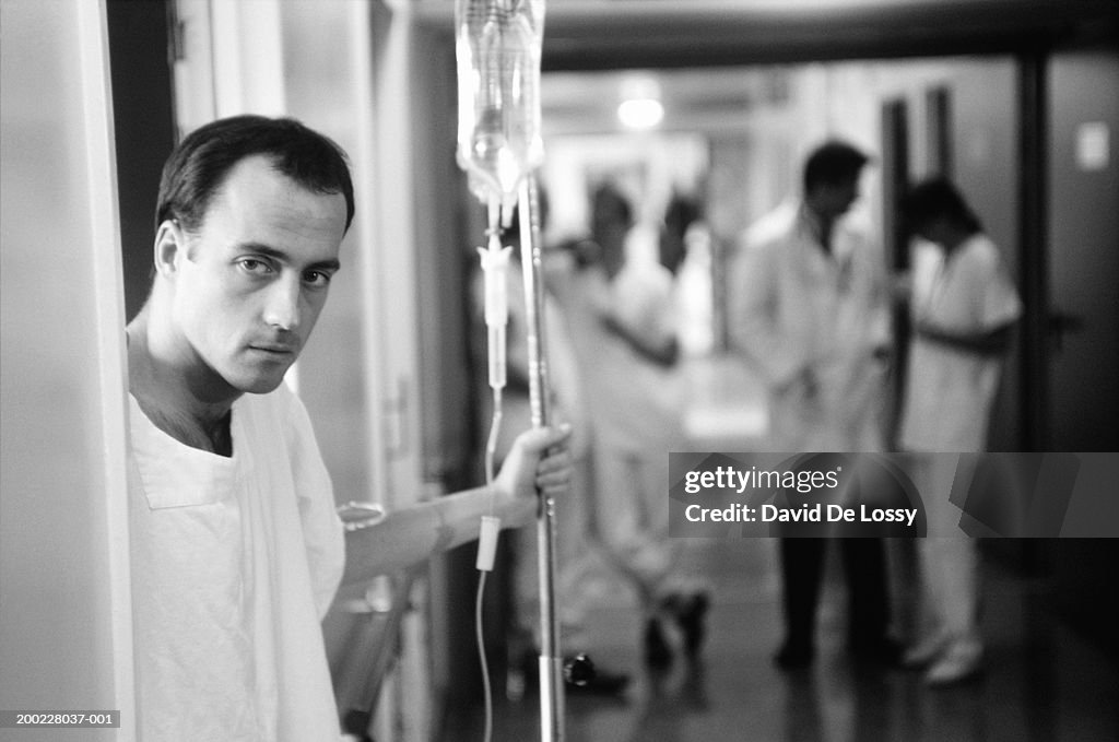 Patient in hospital holding IV drip, (B&W)