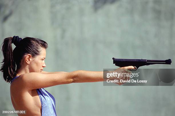 young woman aiming pistol, side view - firing handgun stock pictures, royalty-free photos & images