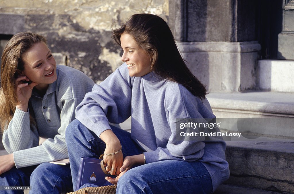 Two teenage girls (16-17) sitting on stairs, outdoors