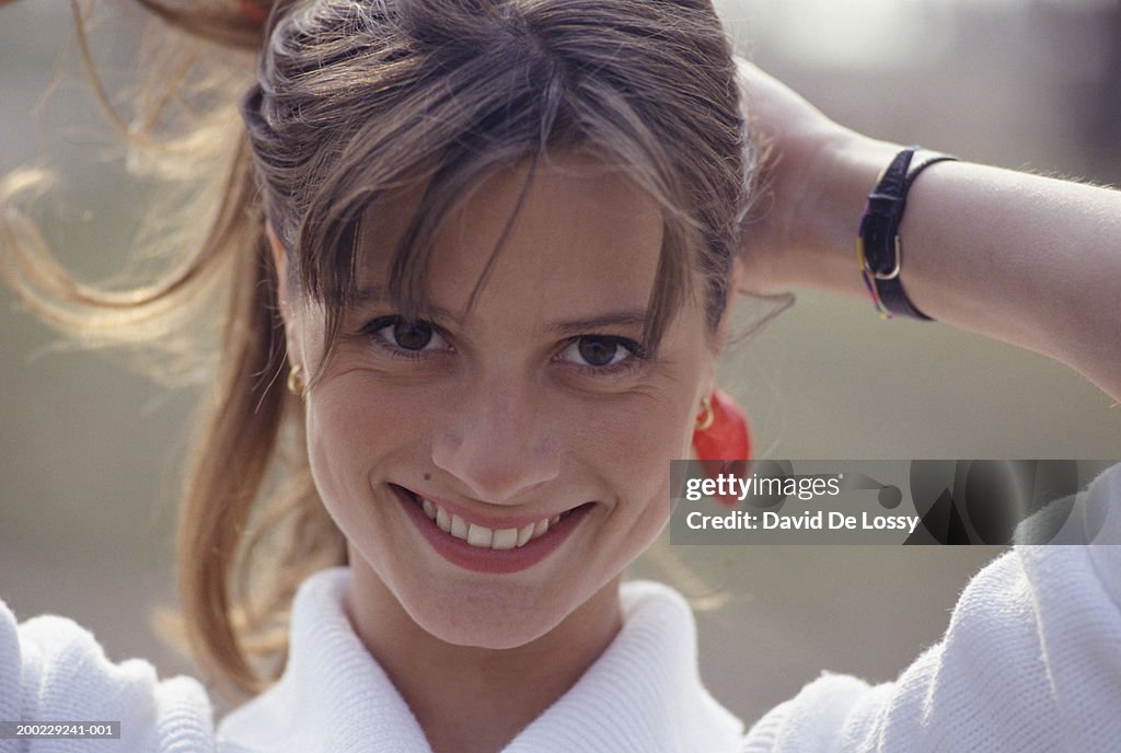 Young woman, hands on back of head, smiling, portrait