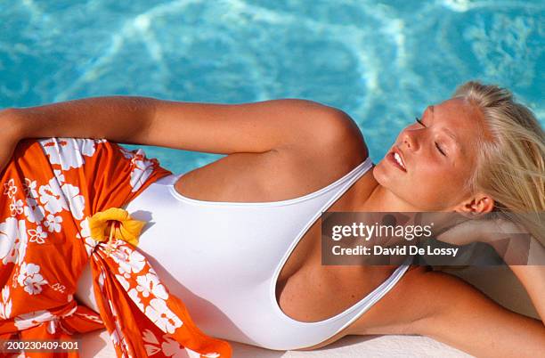 young woman lying by swimming pool, close-up - sarong stock pictures, royalty-free photos & images