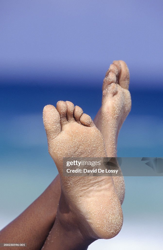 Woman relaxing at beach, low section, close-up