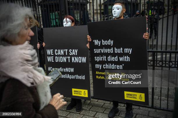 Amnesty International UK protesters hold placards outside Downing Street to raise attention to the plight of Palestinian civilians in the Gazan...