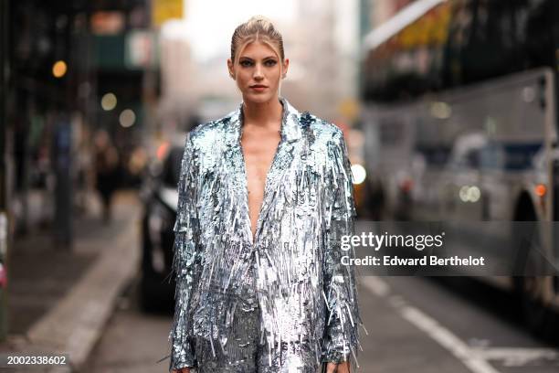 Devon Windsor wears a silver shiny glitter fringed oversized blazer jacket , matching suit flared pants , outside La Pointe , during New York Fashion...