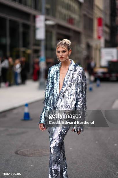 Devon Windsor wears a silver shiny glitter fringed oversized blazer jacket , matching suit flared pants , outside La Pointe , during New York Fashion...