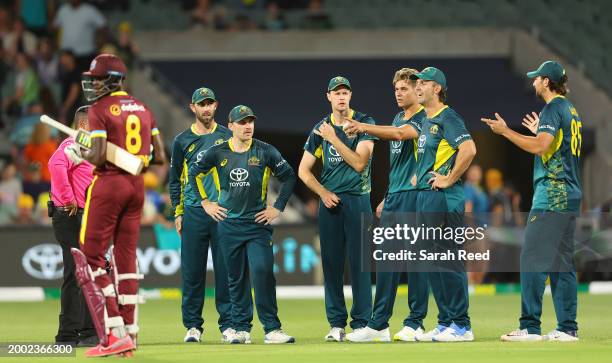 Mitchell Marsh of Australia stands with his team as the umpire gets clarification on the run out of Alzarri Joseph of the West Indies by Spencer...