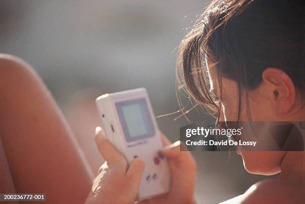 woman playing with handheld video game - pocket electronic game stock pictures, royalty-free photos & images