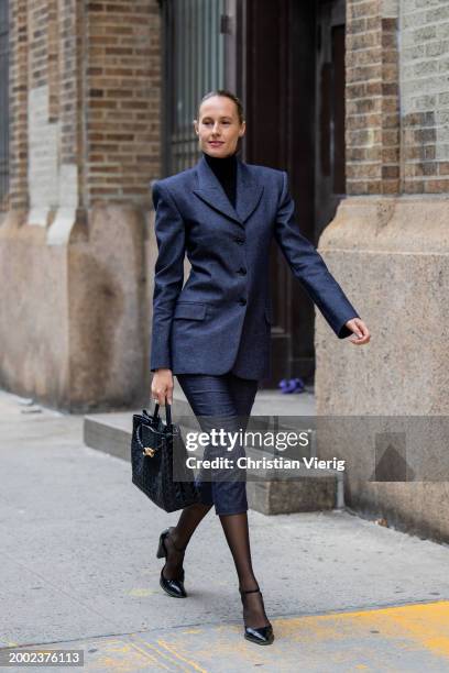 Guest wears navy tailored blazer, cropped pants, tights, bag outside Proenza Schouler on February 10, 2024 in New York City.