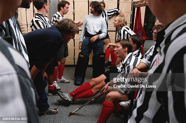 hockey players with coach in locker room, smiling - coaching formacion stock-fotos und bilder