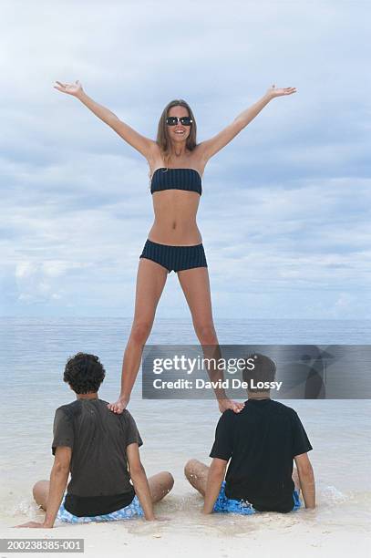 young woman standing on men's shoulders - female with group of males stock pictures, royalty-free photos & images