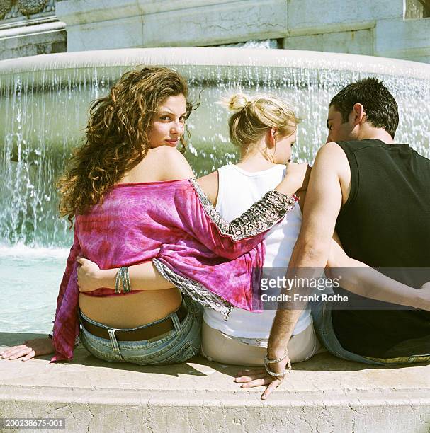 friends sitting by fountain, portrait of woman looking over shoulder - affair stock pictures, royalty-free photos & images