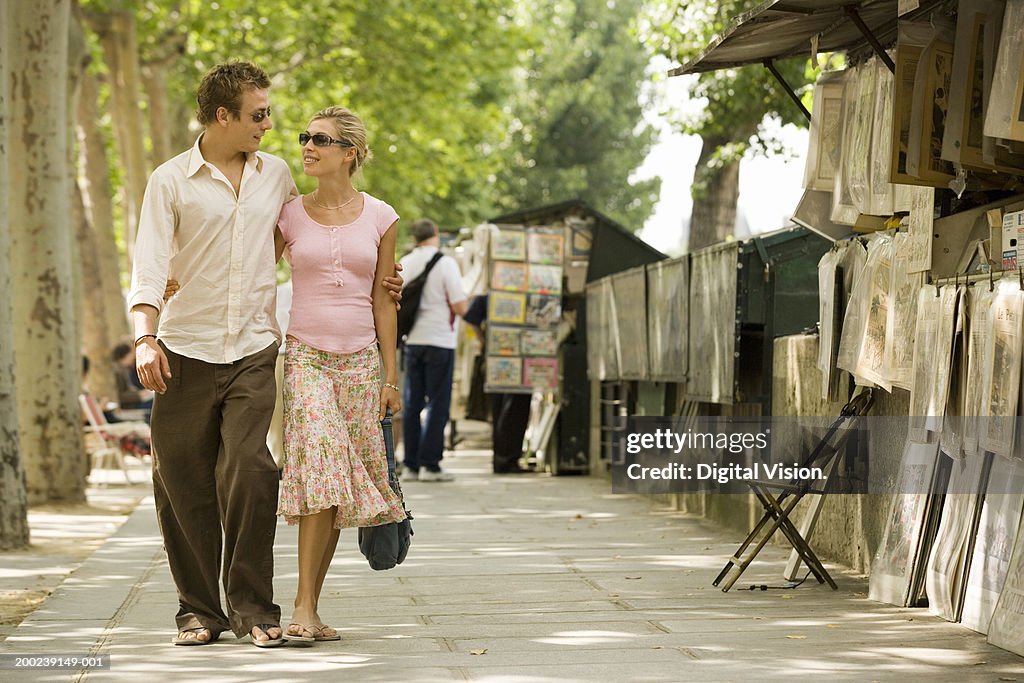 Couple walking by street market, smiling at each other