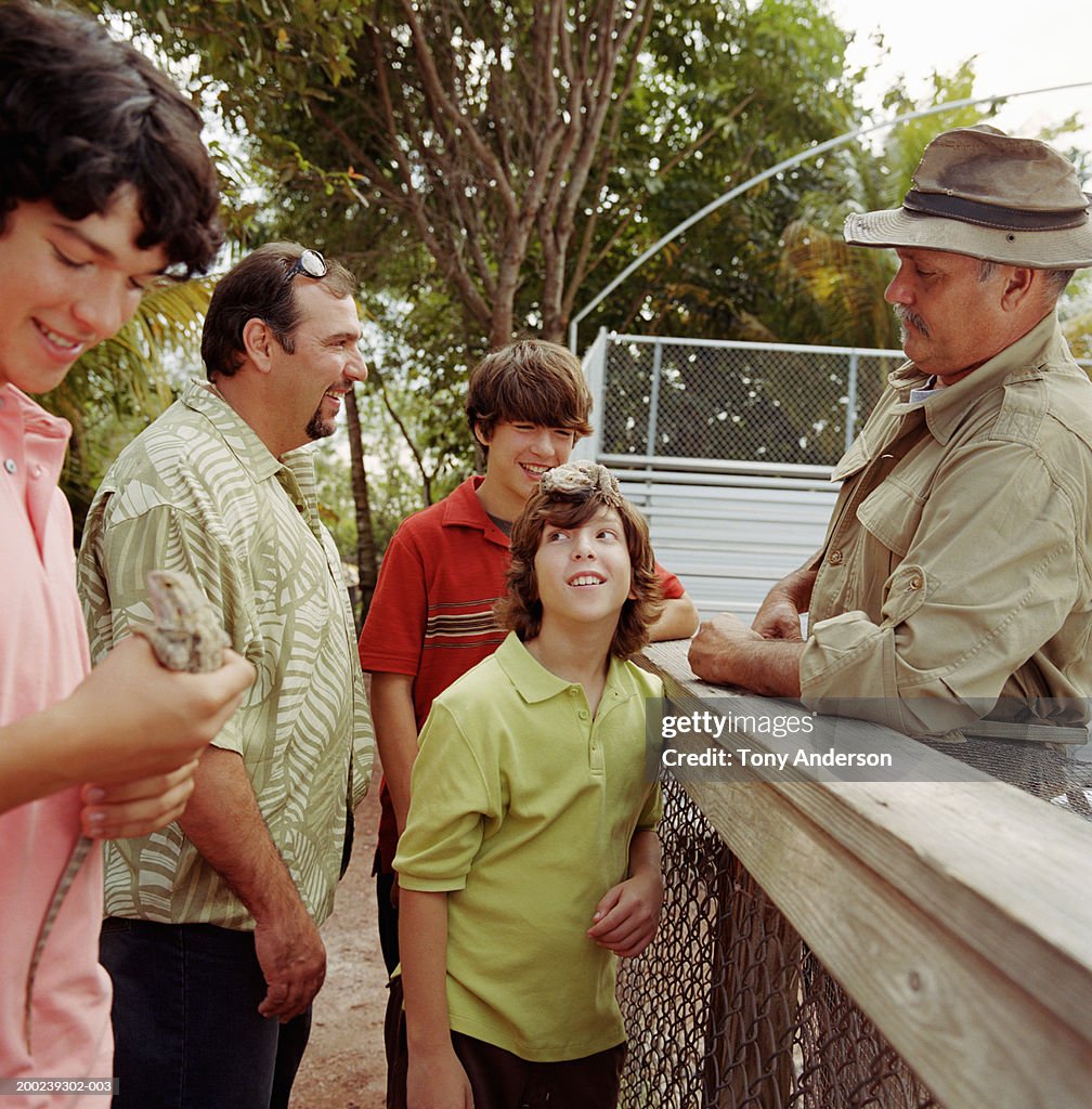 Father and sons (10-17) with gamekeeper, teenage boy holding lizard
