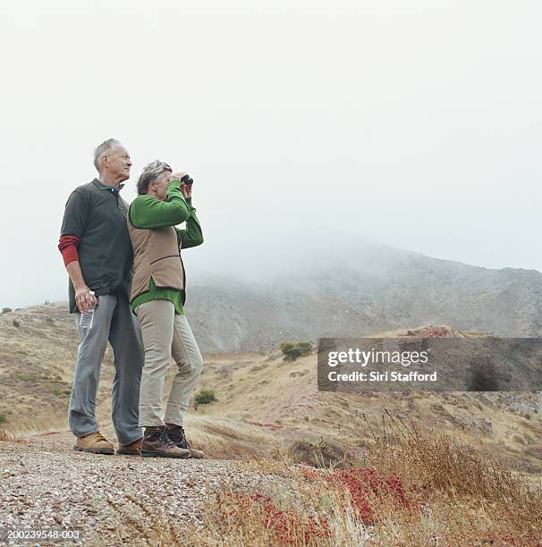 mature couple hiking, woman with binoculars - gray shoe stock pictures, royalty-free photos & images