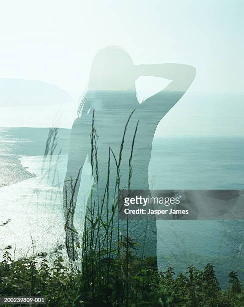 woman standing on cliff edge, rear view (double exposure) - cliff edge stock-fotos und bilder
