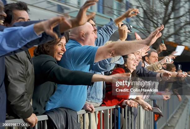 crowd of people leaning over fence, arms outstretched - autograph hunter stock pictures, royalty-free photos & images