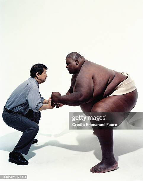 sumo wrestler and businessman facing off, side view - sumo stock pictures, royalty-free photos & images