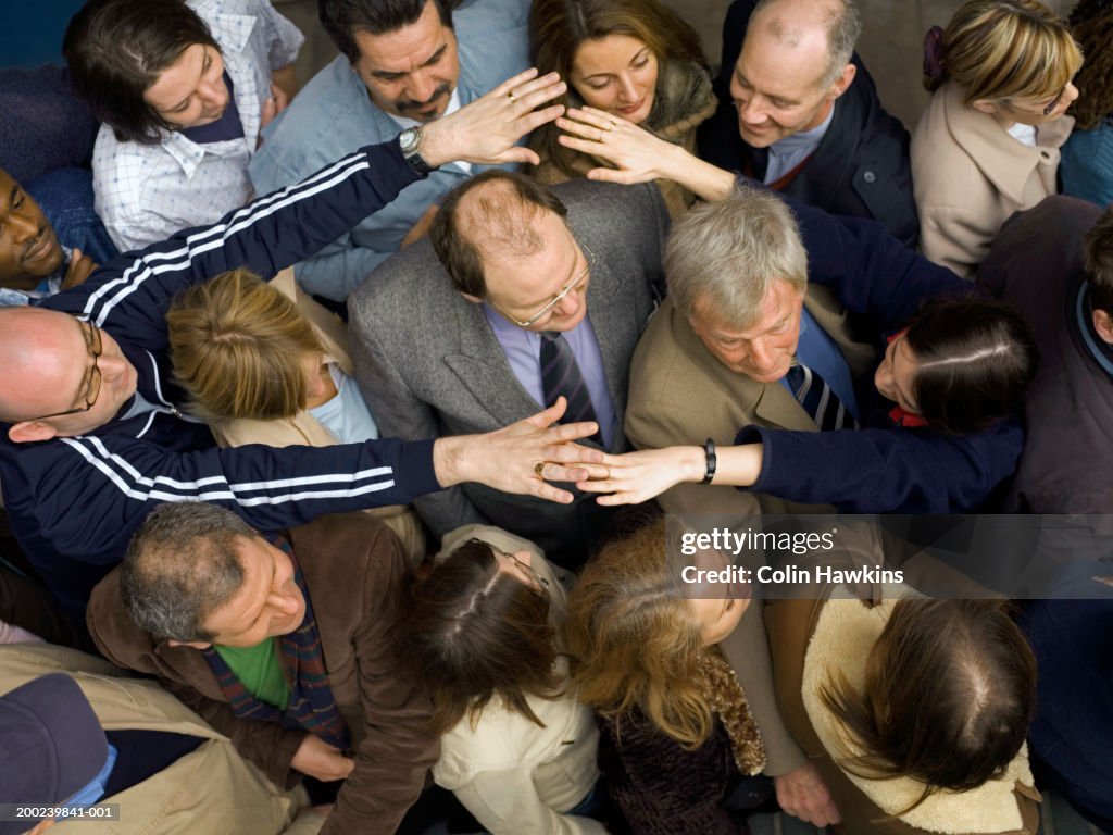 Couple reaching for each other over crowd of people, overhead view