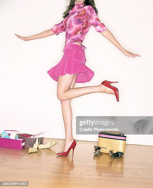 young woman trying on shoes in shop, standing on one leg, mid section - women trying on shoes 個照片及圖片檔