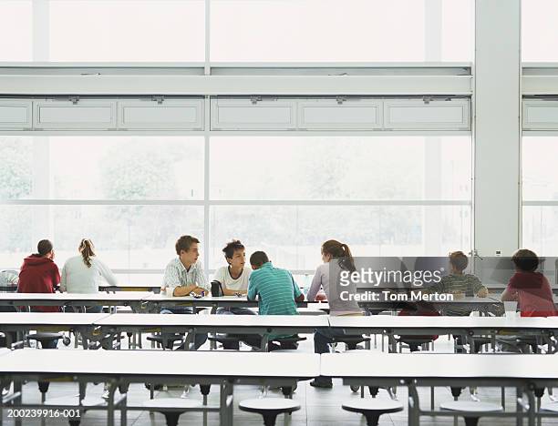 schoolchildren (12-16) sitting at tables in canteen - cafeteria stockfoto's en -beelden