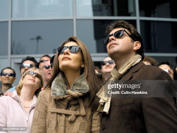 couple wearing sunglasses outdoors, looking up - crowd looking up stock pictures, royalty-free photos & images