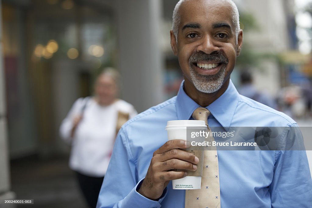 Mature businessman with coffee smiling, portrait, close-up