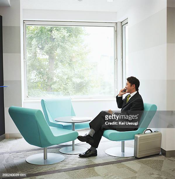 businessman sitting in chair, talking on mobile phone - 背広 ストックフォトと画像
